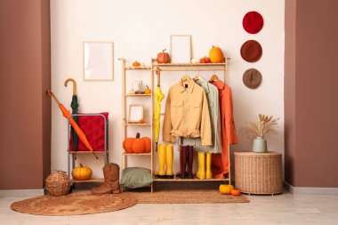 Hasır masa, balkabakları, koridorun iç tarafında elbise ve şemsiyelerle dolu raflar.