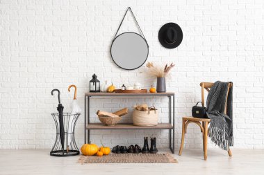 Sandalye, raf ünitesi, balkabağı ve şemsiyeler koridorun içinde.