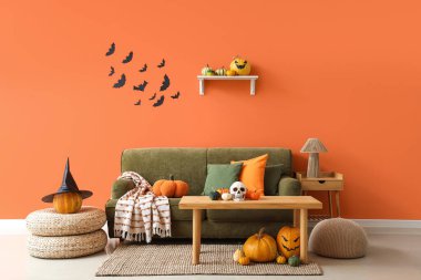 Cadılar Bayramı için dekore edilmiş oturma odasının içi yeşil kanepe, masa ve balkabaklarıyla dolu.