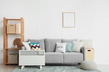 Koltuğun yanında elektrikli konveksiyon ısıtıcısı ve oturma odasında raf ünitesi var.