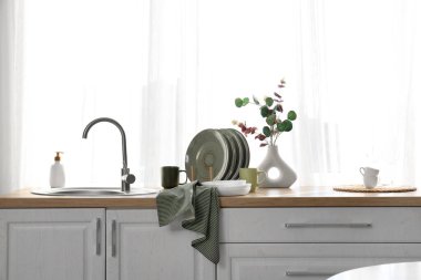 Temiz havlu ve mutfak lavabosunun yanında bir sürü bulaşık var.