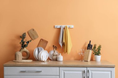 Turuncu duvarda asılı temiz havlular ve mutfakta bir sürü bulaşık.