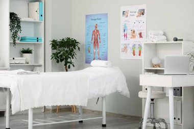Çalışma yeri, kanepe, raf ünitesi ve modern tıp merkezinin duvarlarında posterleri olan masaj terapistinin bürosu.