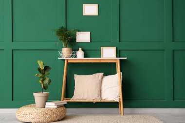 Yastıklı ahşap bank, oda yeşil duvarın yanında sedir ve çiçek.