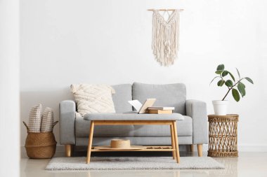 Gri kanepe, hasır masa ve yumuşak bankta kitaplar olan oturma odasının içinde.