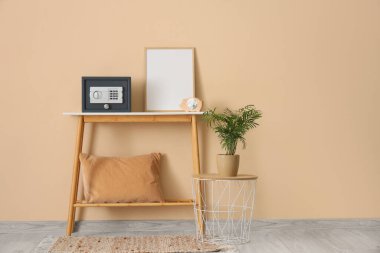 Kumbaradaki para dolu modern kasa ve bej duvarın yanındaki masada resim.