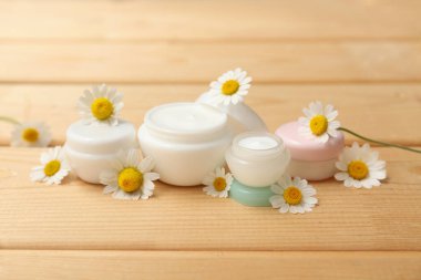 Kavanozlar dolusu papatya çayı ve ahşap arka planda çiçekler.