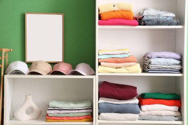 Dolapta kepleri ve katlanmış kıyafetleri olan raflar.