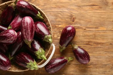 Tahta arka planda taze olgun patlıcanlarla dolu bir sepet.