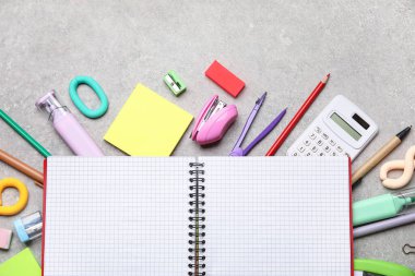 Gri grunge arkaplan üzerinde boş defter ve farklı okul kırtasiyesine sahip kompozisyon, yakın plan