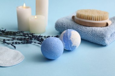 Lavanta banyosu bombaları, pamuk yastıklar ve yanan mumlar mavi arka planda, yakın plan