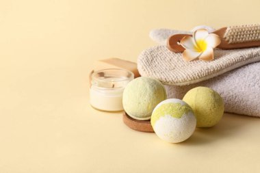 Banyo bombalı kompozisyon, yanan mumlar ve sarı arka planda masaj eldiveni, yakın plan.