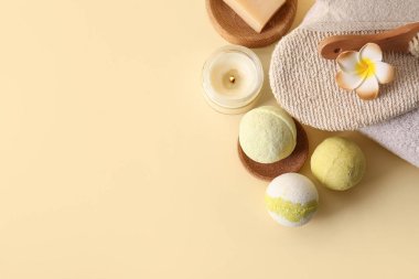 Banyo bombalı kompozisyon, yanan mumlar ve sarı arka planda masaj eldiveni, yakın plan.