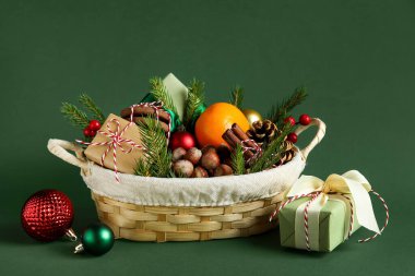 Ürünleri olan hediye sepeti ve yeşil arka planda Noel dekoru.