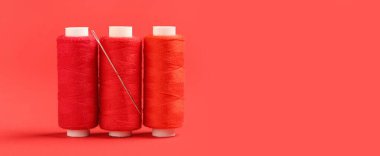 Kırmızı arkaplan üzerinde iplik ve iğne makaraları metin için boşluk