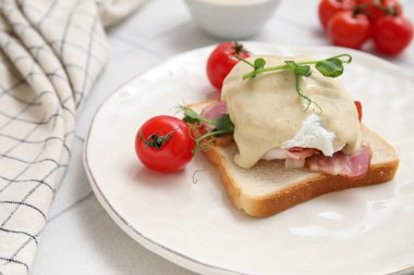 Lezzetli yumurta, Benedict ve beyaz fayanslı domates tabağı.