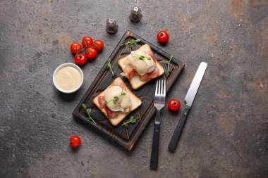 Lezzetli yumurtalardan oluşan ahşap tahta bir tahta. Pastırmalı ve kirazlı domatesli Benedict.