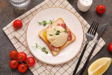 Koyu arkaplanda pastırma ve kiraz domatesli lezzetli Benedict yumurtası.