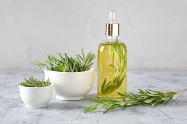 Beyaz duvara karşı gri grunge masasında gerekli yağ şişesiyle taze biberiye.