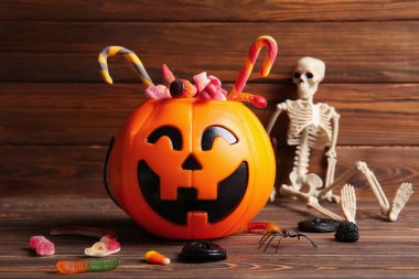 Farklı tatlı şekerlerle dekoratif balkabağı ve ahşap arka planda iskelet. Cadılar Bayramı