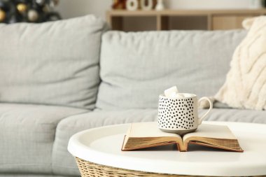 Oturma odasındaki masada kitap olan bir fincan kakao, Noel için dekore edilmiş, yakın plan.