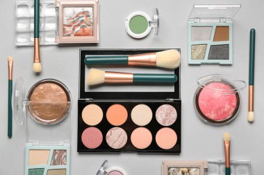 Beyaz arka planda kozmetik ürünleri ve farklı makyaj fırçaları olan kompozisyon, yakın plan