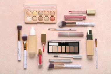 Pembe grunge arka planında farklı makyaj fırçaları ve kozmetik ürünleri olan kompozisyon