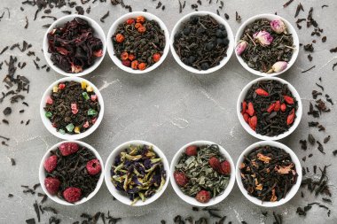 Gri arkaplanda farklı meyve çayları olan kaseler