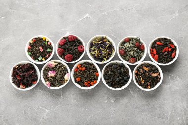Gri arkaplanda farklı meyve çayları olan kaseler