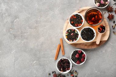 Farklı meyve çaylarıyla dolu kaseler ve gri grunge arka planda demlenmiş içecekler.