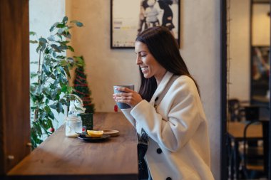 Sabahları restoranda kahve içen mutlu kadın.