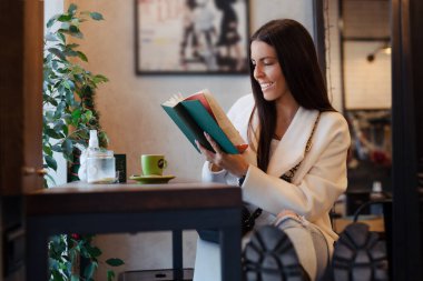 Genç güzel kadın Cafe ilginç bir kitap okuma
