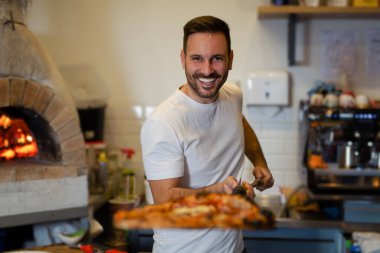 A process of preparing pizza by a chef.Italian traditional pizza is cooked in a stone wood-fired oven.