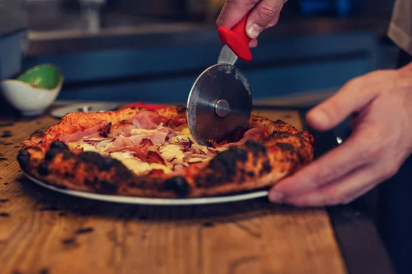 Pizza being cut by pizza cutter. Close up of crust and pizza