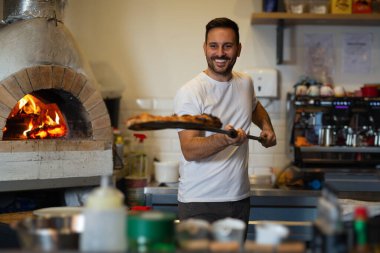 A process of preparing pizza by a chef.Italian traditional pizza is cooked in a stone wood-fired oven.