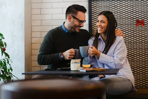 Happy couple drinking coffee in cafe. Smiling man and woman having breakfast together.