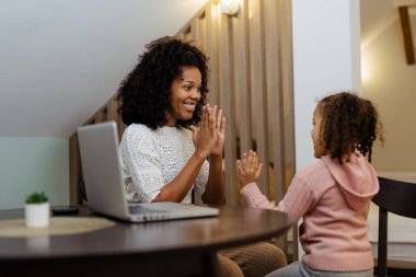 Afrikalı kadın ve küçük kızı gülümseyip ellerini çırpıyor.