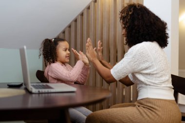 Afrikalı kadın ve küçük kızı gülümseyip ellerini çırpıyor.