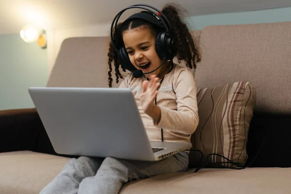 Χαρούμενο Κοριτσάκι Ακουστικά Που Κάθεται Στον Καναπέ Ένα Φορητό Υπολογιστή — Φωτογραφία Αρχείου