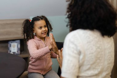 Afrikalı kadın ve küçük kızı gülümseyip ellerini çırpıyor.