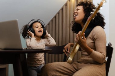 Anne ve kızı evde elektro gitar çalıyorlar, mutlu bir aile.