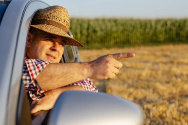 Hasır şapkalı genç adam kamyon sürüyor ve plantasyonlarına bakıyor..