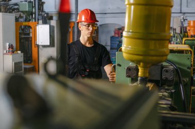 Büyük endüstriyel makinelerle metal levha fabrikasında çalışan bir atmosfer..