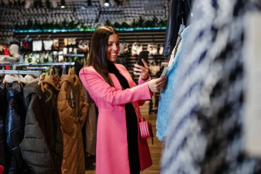 Galeride elbise seçen genç bir kadın.