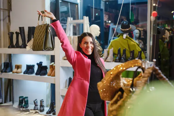 Smiling woman choosing leather bag in shop