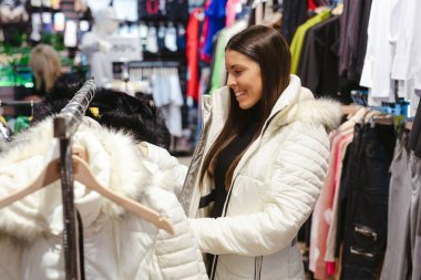 Güzel, genç, esmer kadın dükkandan kışlık kıyafet seçiyor..