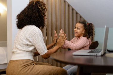 Genç bir kadın oturma odasında bayan arkadaşına beşlik çakıyor.