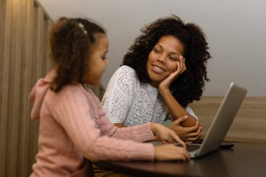 Afrika kökenli Amerikalı anne ve kız evde dizüstü bilgisayar kullanıyorlar..