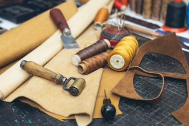 Ayakkabı tamirhanesinde deri ve aletler. Ahşap zemin üzerinde deri el aletleri seti.