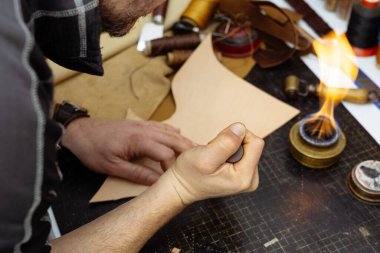 Ayakkabıcı ya da zanaatkar işçilere yakın çekim. Eski ahşap masada deri el işi aletleri.
